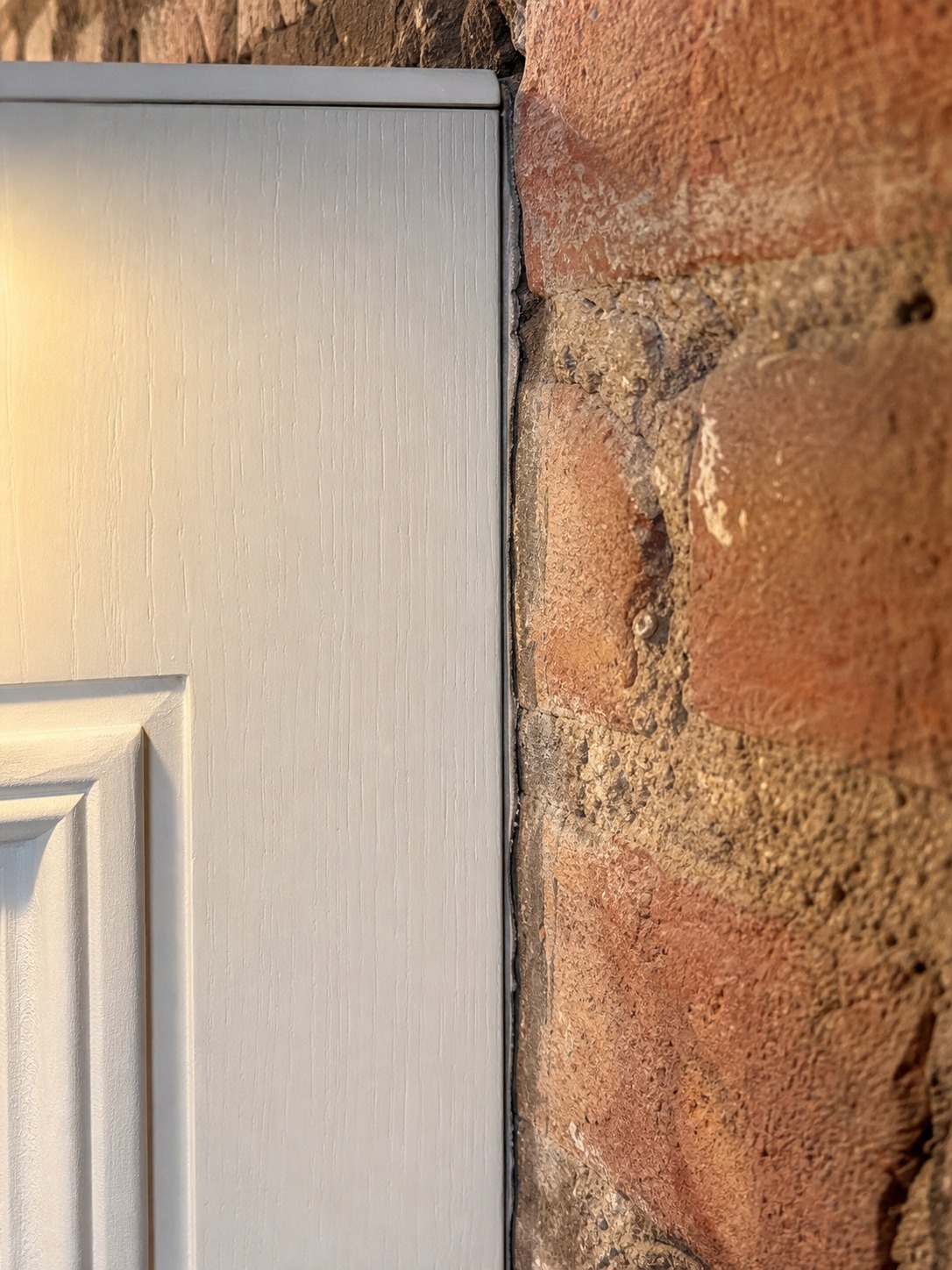 Close detail of an oak cabinet panel scribed tightly to an irregular exposed brick wall.