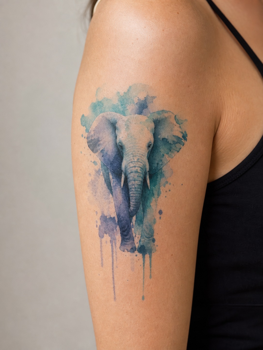 Watercolor elephant tattoo with teal and indigo paint splashes.