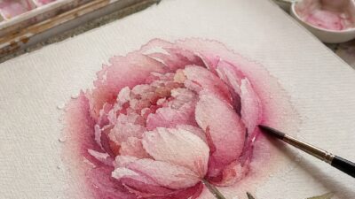 Pink watercolor peony painting in progress on cold-press paper with soft wet-on-wet edges.