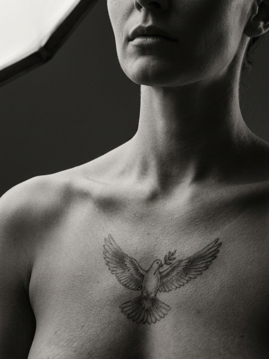 Delicate dove in flight on a woman's upper chest and sternum.