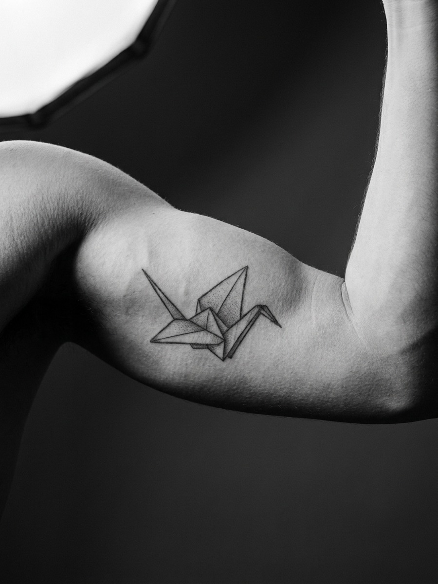 Geometric origami-style bird on a man's inner bicep.