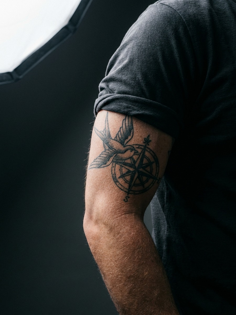 A bird in flight above a detailed compass rose on a man's inner bicep.