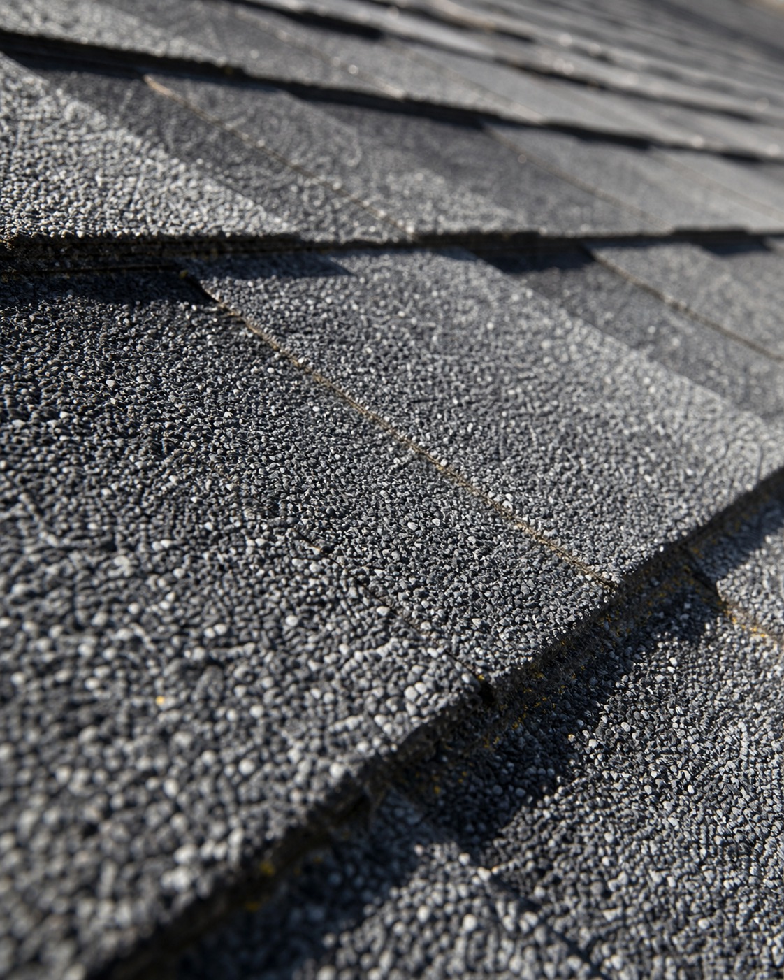 Close-up of layered charcoal architectural shingles with visible granule texture