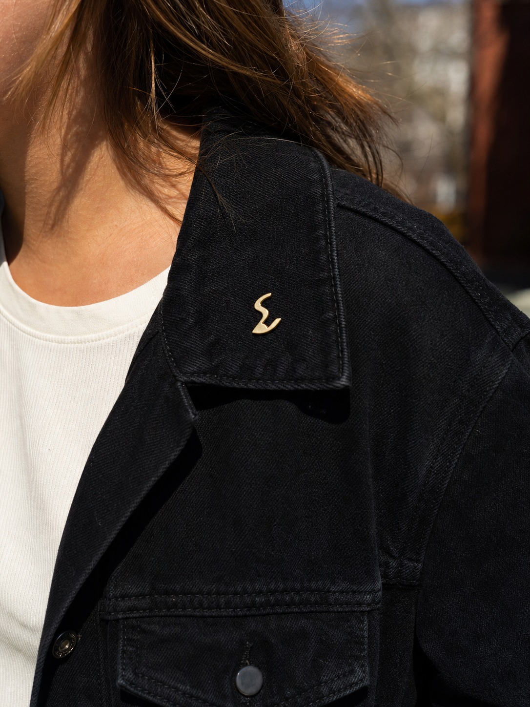 Branded pin on jacket A person wearing a small abstract branded pin on a jacket in an everyday setting. | Sky Rye Design A person wearing a small abstract branded pin on a jacket in an everyday setting.