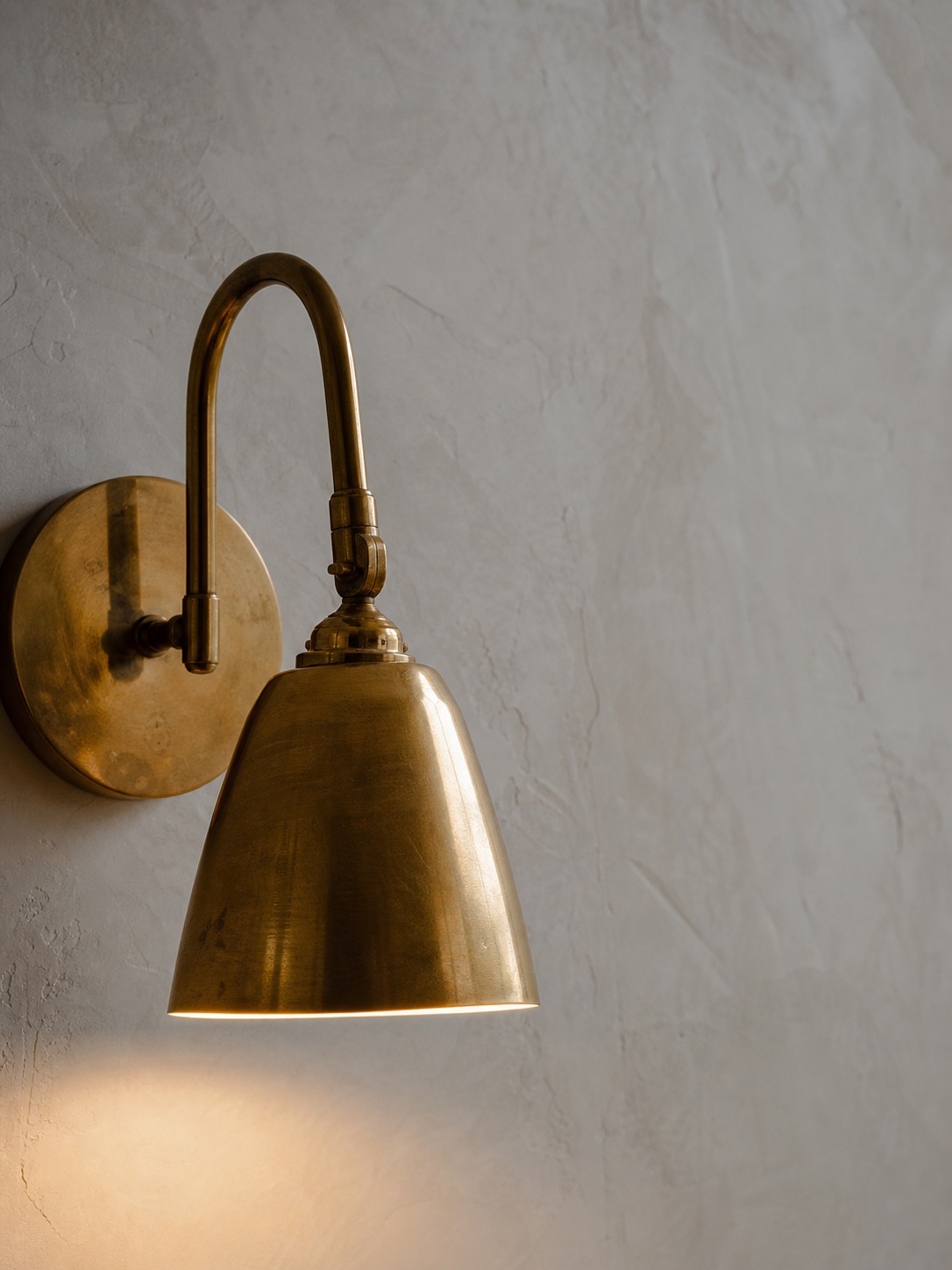 Brass fixture still life A close-up still life of a brass light fixture against a plain plaster wall with warm light and generous negative space. | Sky Rye Design A close-up still life of a brass light fixture against a plain plaster wall with warm light and generous negative space.