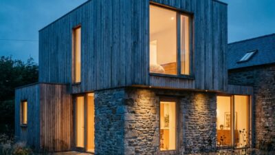 Completed home addition at blue hour with original and new volumes reading as one unified silhouette.