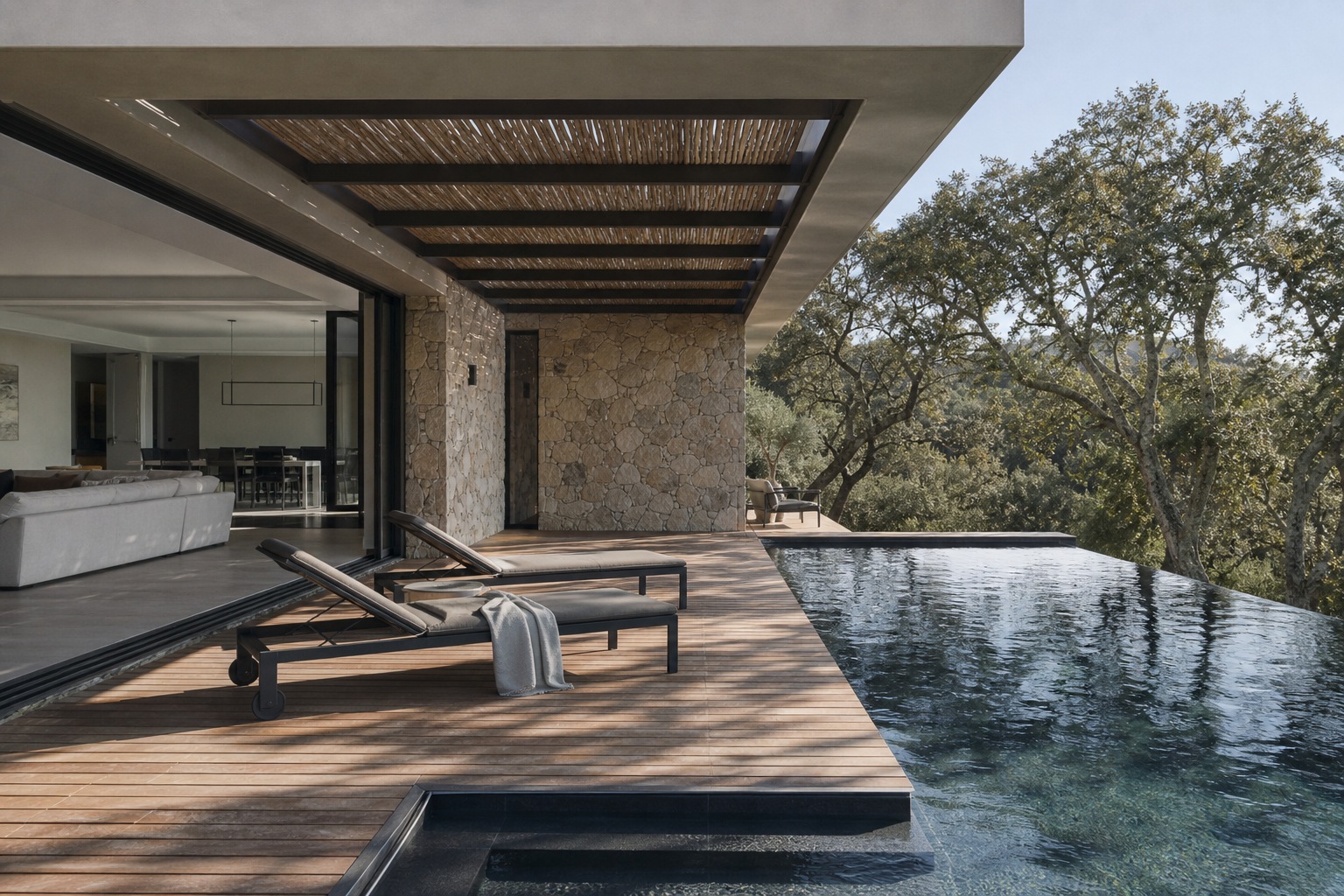 Pool terrace covered outdoor room Covered outdoor lounge beside a dark infinity-edge pool with oak trees beyond the terrace. | Sky Rye Design Covered outdoor lounge beside a dark infinity-edge pool with oak trees beyond the terrace.