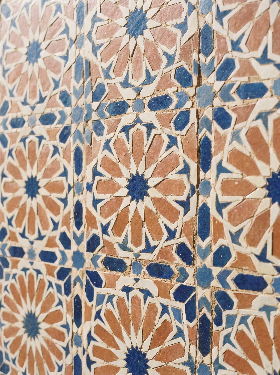 Fes zellij tilework geometric detail Close crop on traditional Fes zellij tilework showing an intricate repeating geometric pattern in terracotta, cobalt, and cream | Sky Rye Design Close crop on traditional Fes zellij tilework showing an intricate repeating geometric pattern in terracotta, cobalt, and cream