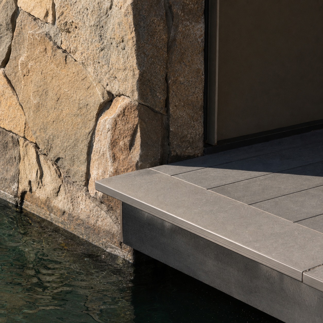 Close-up of a floating platform edge meeting a stone-clad building base above the water.
