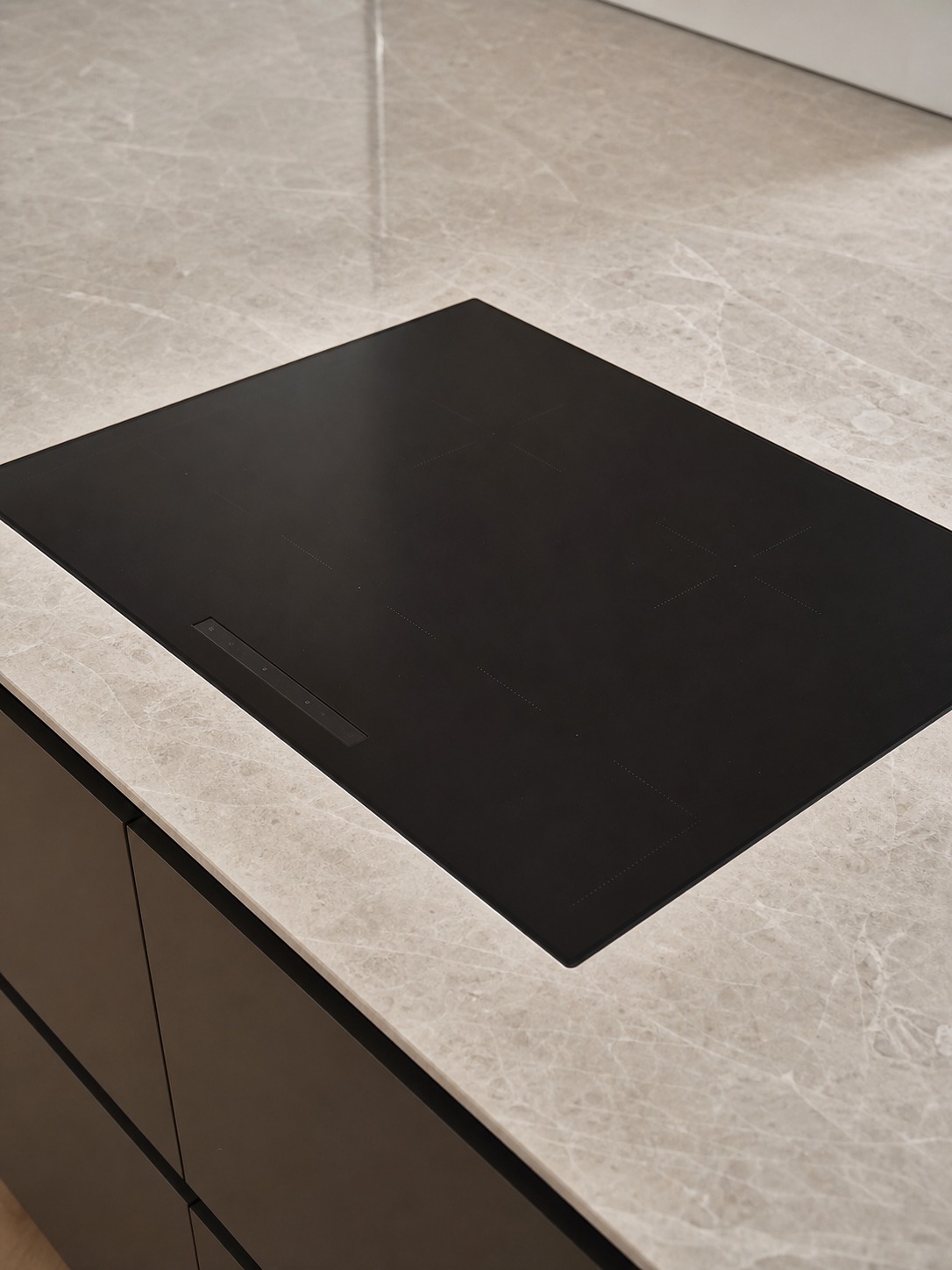 Flush induction cooktop in a stone countertop Flush induction cooktop set into a veined stone countertop with minimal control clutter. | Sky Rye Design Flush induction cooktop set into a veined stone countertop with minimal control clutter.