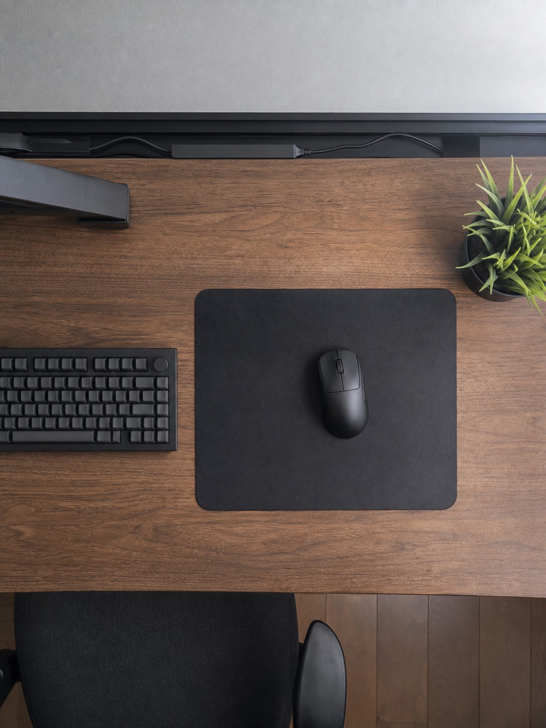Overhead gaming desk layout showing a mousepad, keyboard, wireless mouse, and rear cable channel