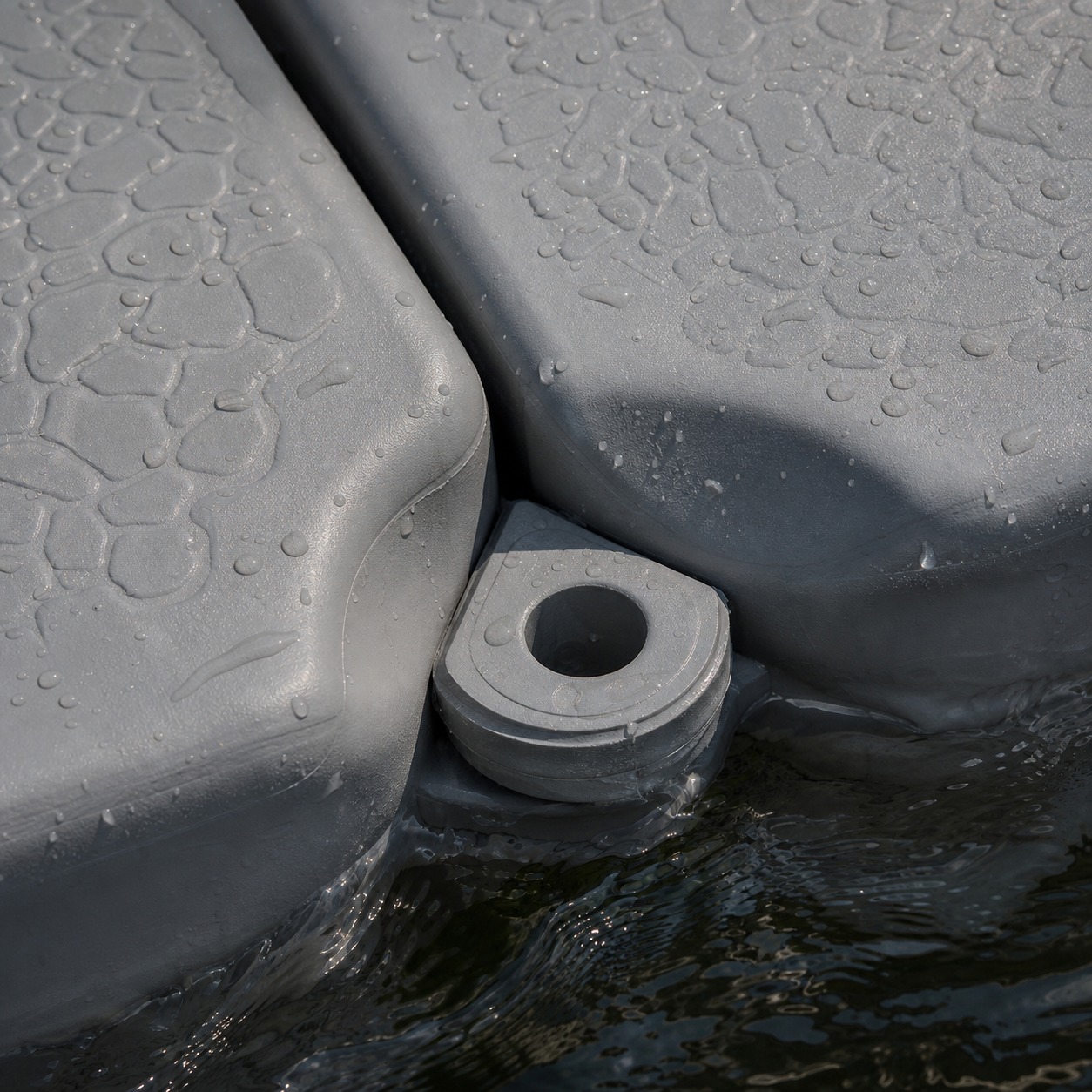 Close-up of interlocking HDPE floating dock modules with water droplets on the textured surface.