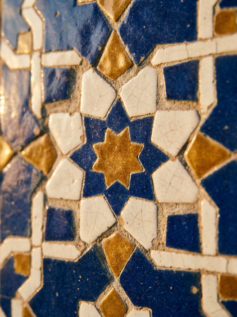 Close-up of cobalt, white, and gold Islamic tessellated tiles with visible grout and glaze texture.