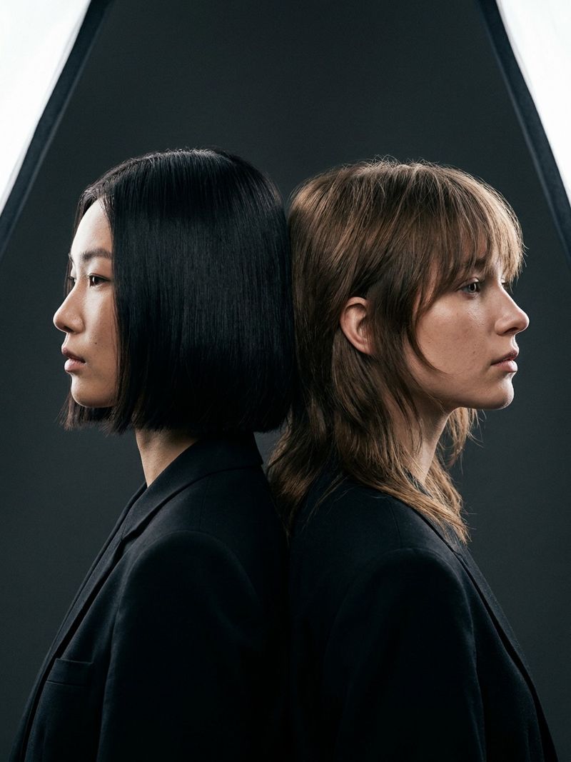 Korean bob versus layered shag comparison Two models standing back to back comparing a blunt Korean bob against a soft layered shag haircut | Sky Rye Design Two models standing back to back comparing a blunt Korean bob against a soft layered shag haircut