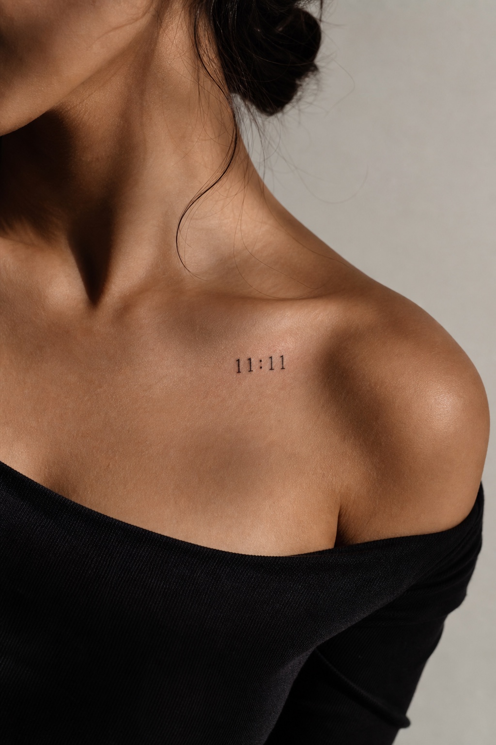 Minimal feminine collarbone tattoo with the lucky number 11:11 in fine black ink