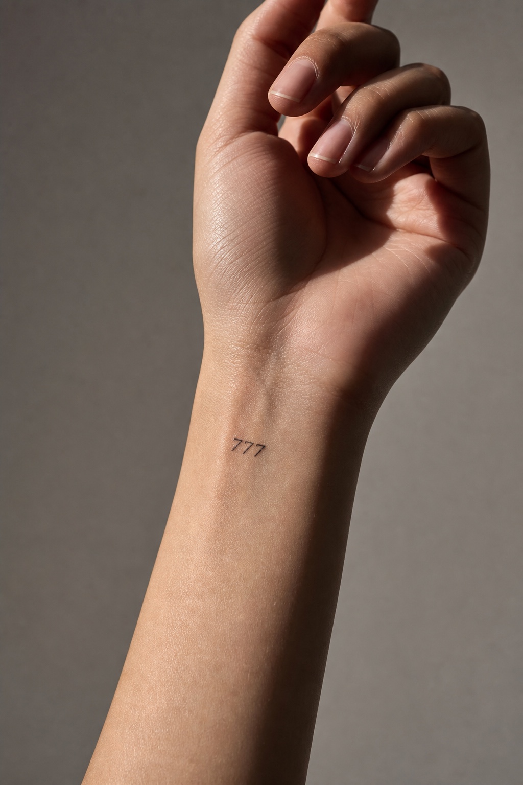 Minimal feminine wrist with a small 777 lucky number tattoo in fine black ink