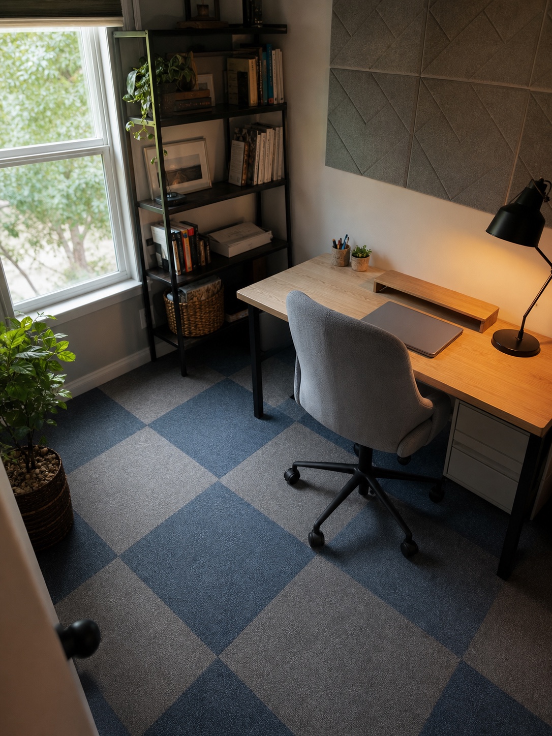 Compact home office with blue gray peel-and-stick carpet tiles beneath a pale oak desk.