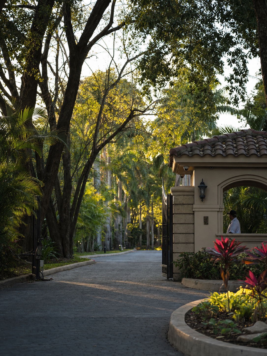 Gated community entrance with tree-lined approach Staffed gatehouse and tree-lined approach road at a tropical luxury residential community | Sky Rye Design Staffed gatehouse and tree-lined approach road at a tropical luxury residential community
