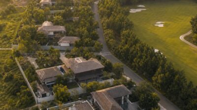 Aerial view of a low-density luxury residential community in tropical Thailand with tree buffers and a golf fairway
