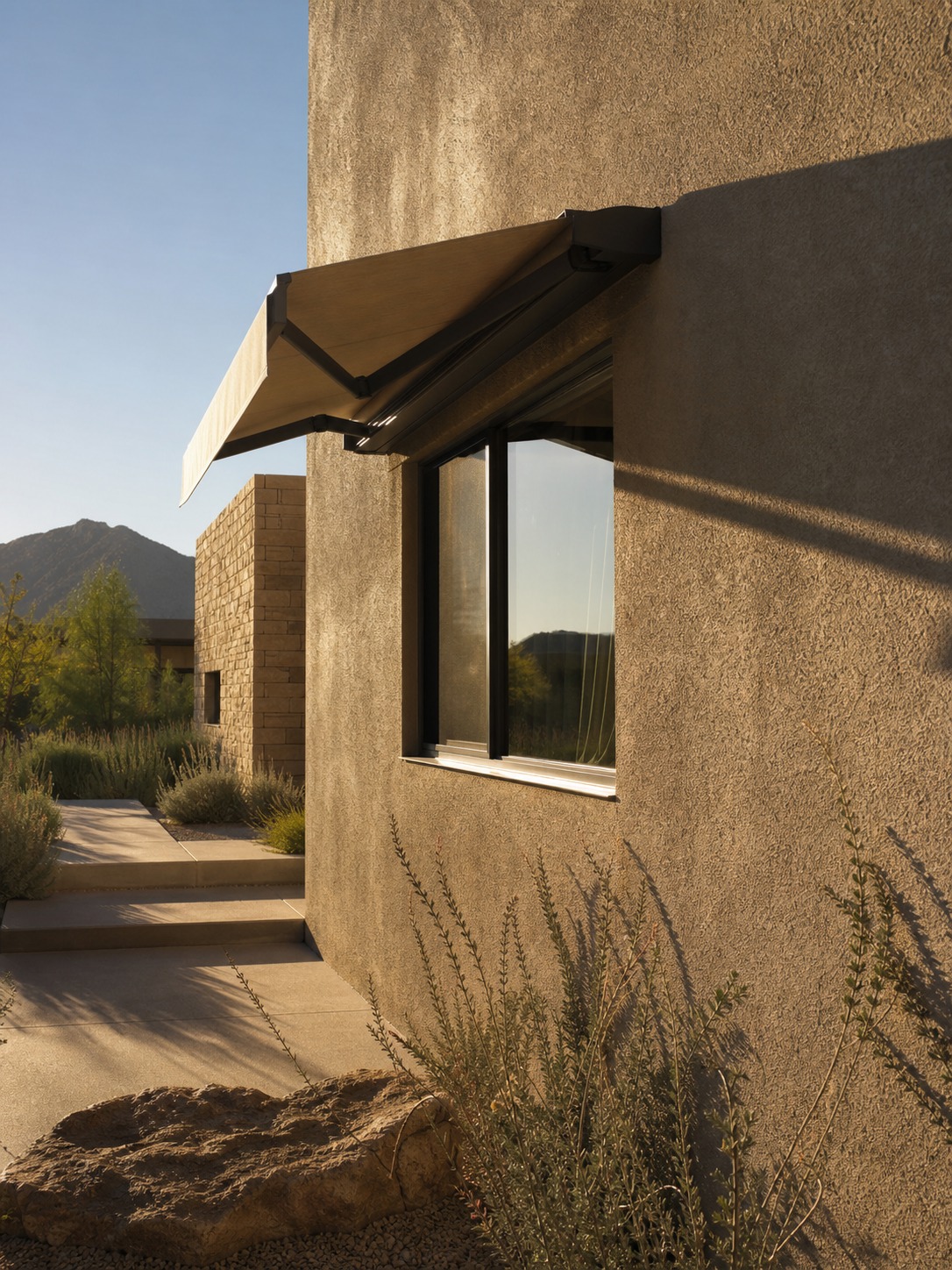 Retractable awning over west-facing window Retractable fabric awning shading a west-facing window on a modern house exterior. | Sky Rye Design Retractable fabric awning shading a west-facing window on a modern house exterior.