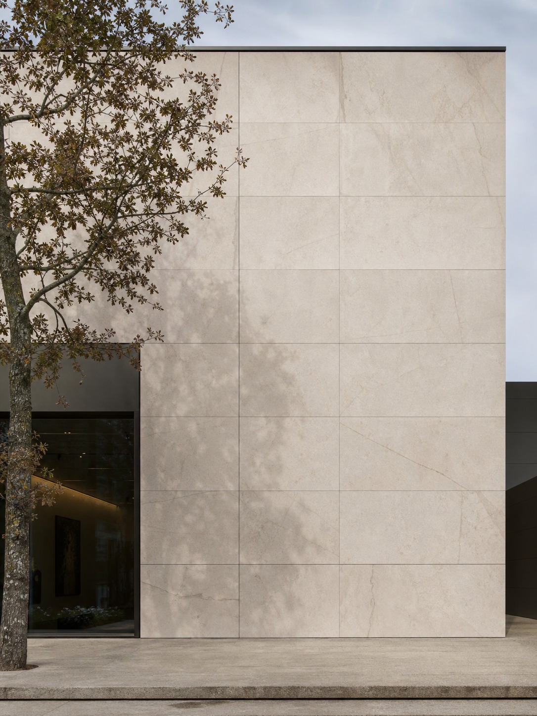 Sintered stone panel facade Minimalist facade with large-format sintered stone panels and soft tree shadows. | Sky Rye Design Minimalist facade with large-format sintered stone panels and soft tree shadows.