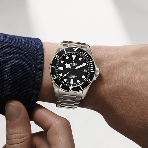 Tudor Pelagos luxury stainless-steel dive watch with black dial and date on wrist, metal bracelet