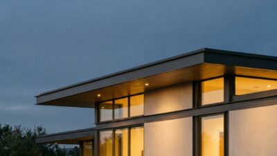 Architectural Digest style photograph of an ultra-modern house exterior at dusk with an unbroken roofline.
