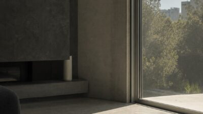 West-facing living room window with solar film filtering afternoon sunlight across a concrete floor.