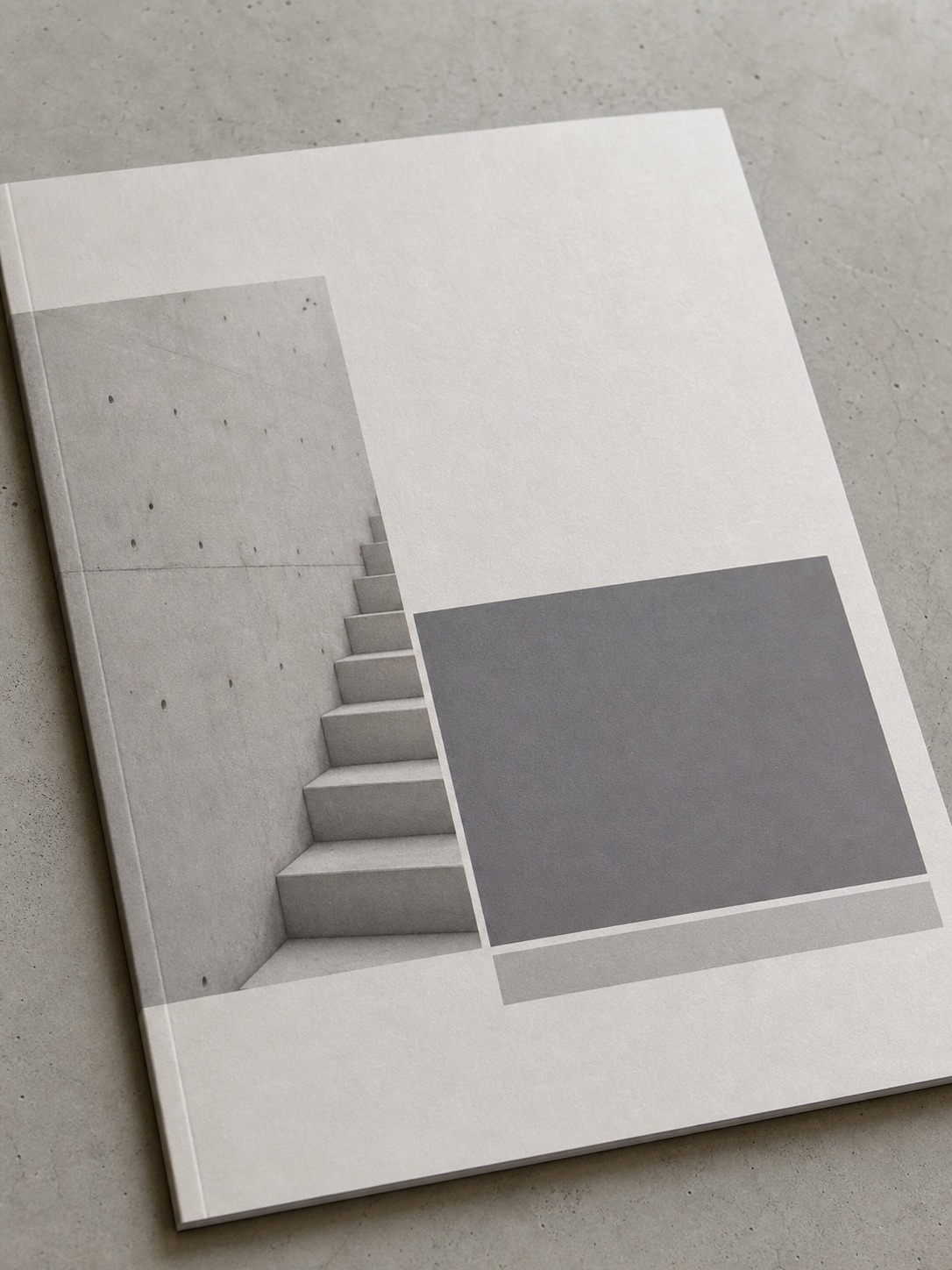 Minimal architecture portfolio cover page photographed on a concrete surface