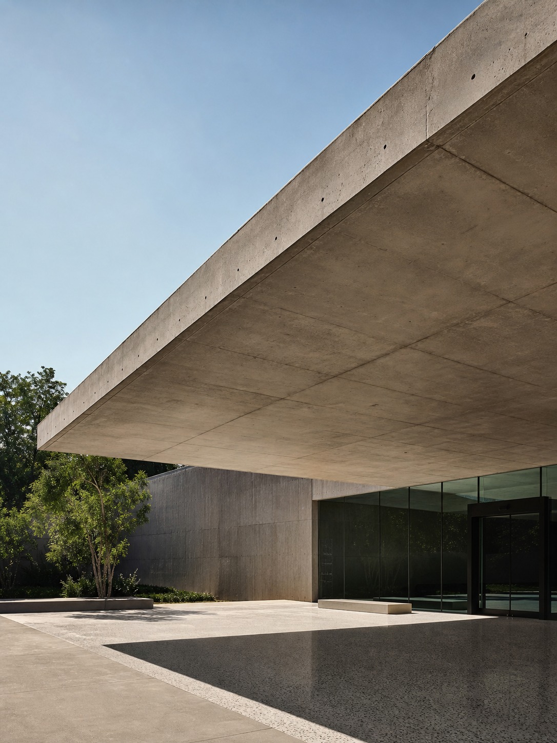 A cantilevered concrete canopy over a museum entrance, seen from below with a sharp shadow across the plaza.