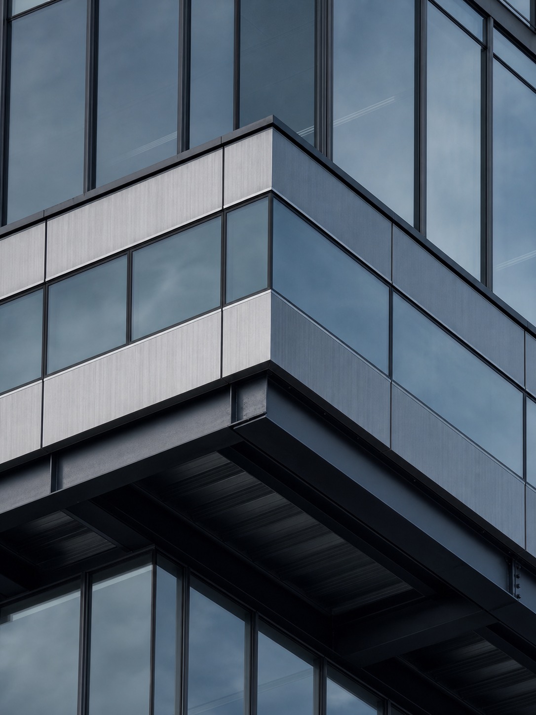 A close exterior view of a Second Phase International building's cantilevered floor plate and glass corner.