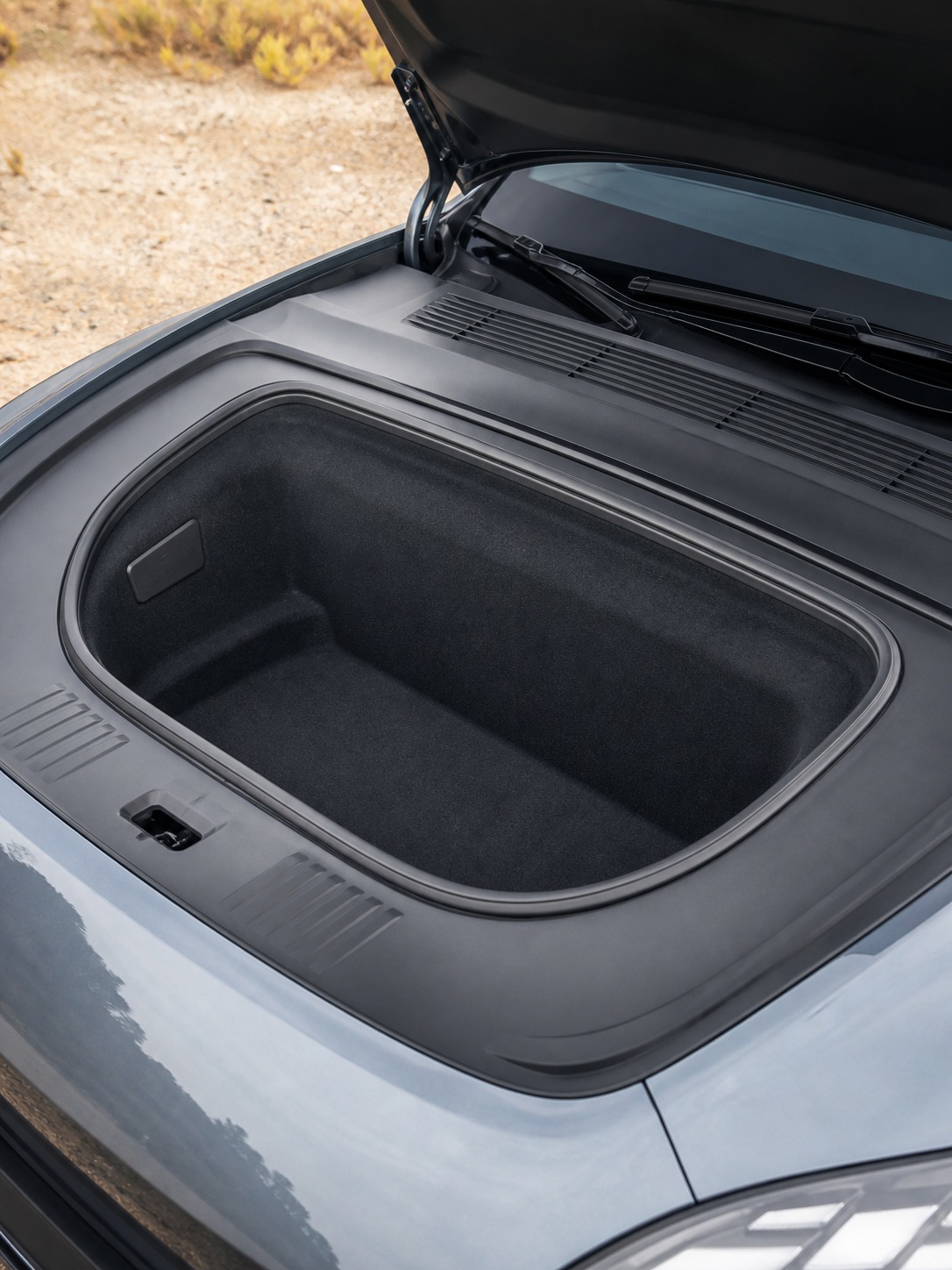 Open electric vehicle frunk showing clean storage space where an engine bay would be.