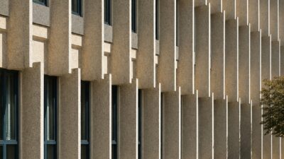 A formalist university facade with decorative concrete sun-screens casting geometric shadows.