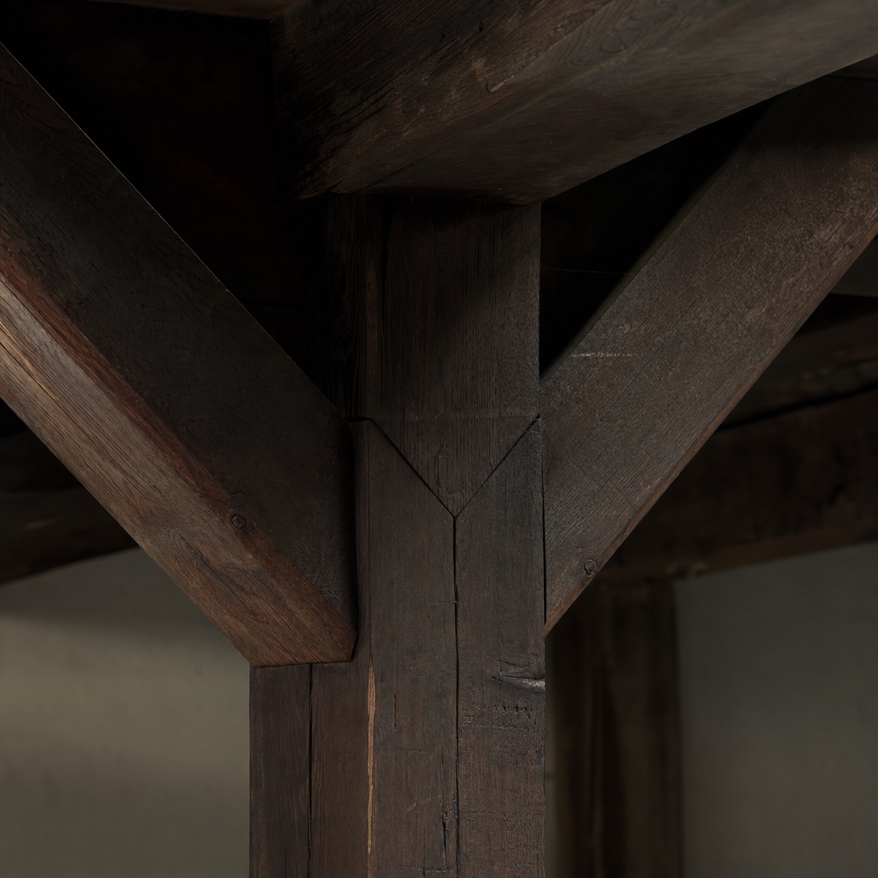 Subtle scarf joint in a shadowed timber-frame corner Dark stained timber-frame corner with a faint scarf joint seam kept subtle in a shadowed area. | Sky Rye Design Dark stained timber-frame corner with a faint scarf joint seam kept subtle in a shadowed area.