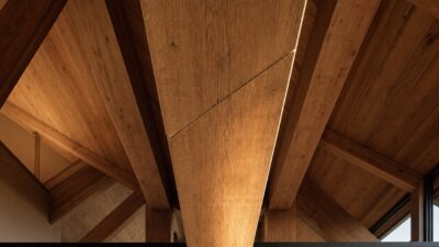 A long oak ridge beam in a modern timber-frame interior with a faint diagonal scarf joint seam under raking light.