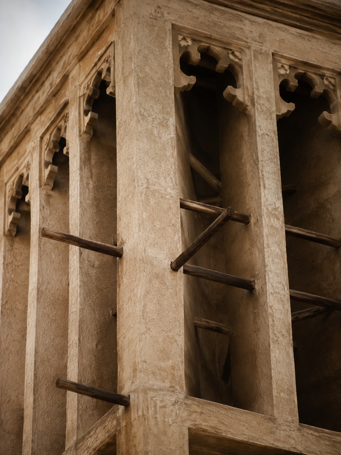 Close view inside a barjeel wind tower showing vertical openings and wooden cross-bracing.