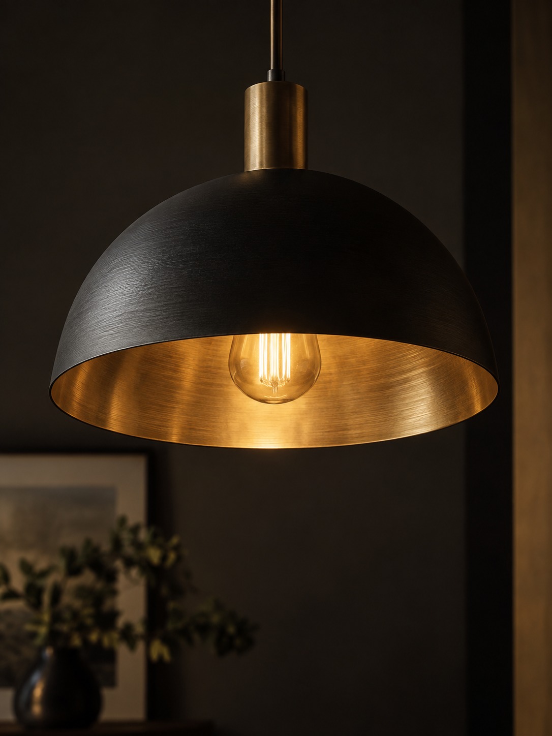 Close view of a black pendant with a gold interior reflecting warm bulb light