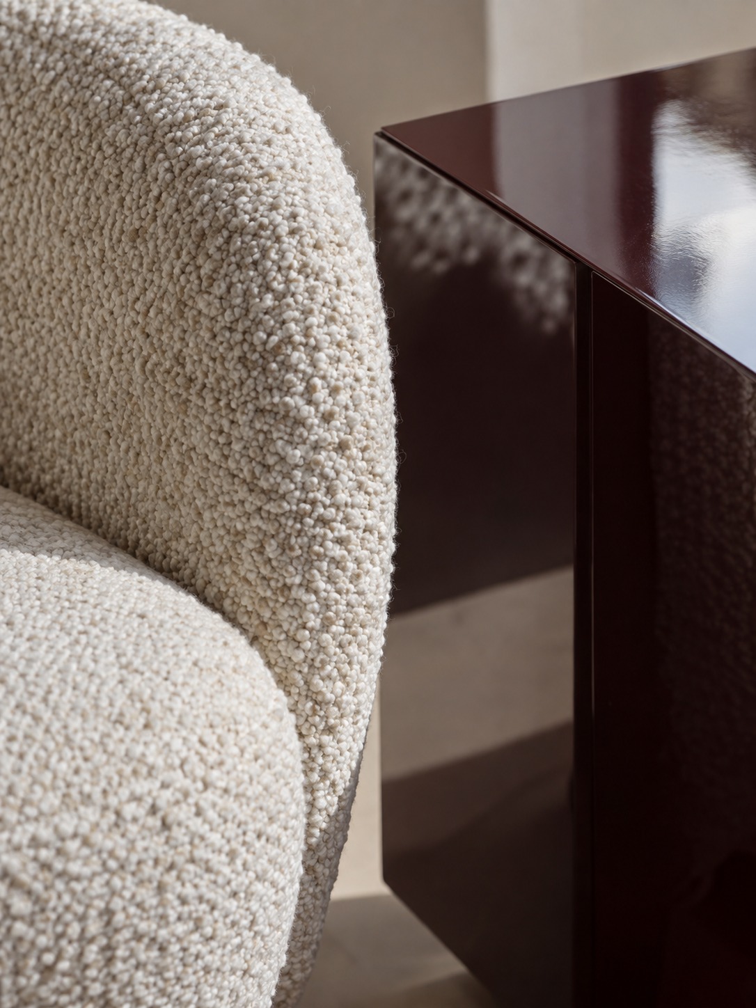 Close-up of textured boucle beside a glossy lacquered console surface