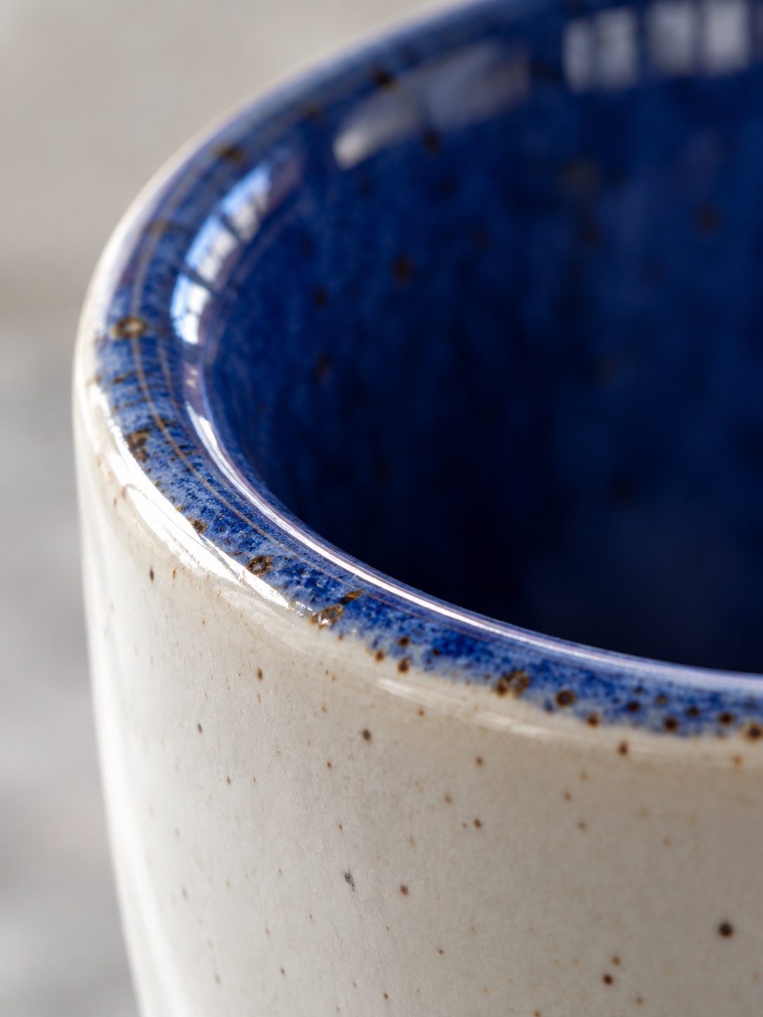 Macro detail of a blue ceramic glaze changing tone around the rim of a mug