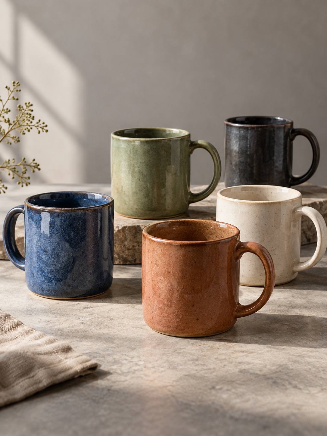 Five ceramic mugs arranged in a coordinated blue green and neutral colour palette