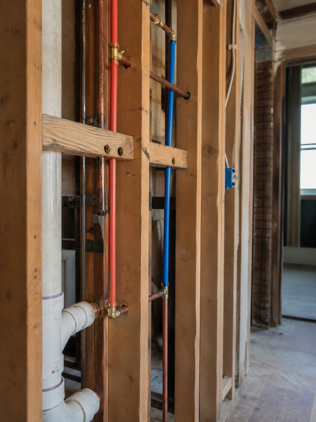 exposed PEX and copper plumbing lines running through open wall framing