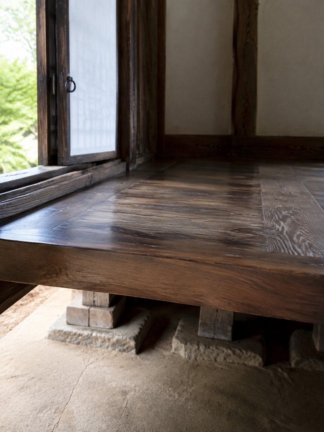 Raised maru wooden flooring in a hanok with natural light from an open sliding door.
