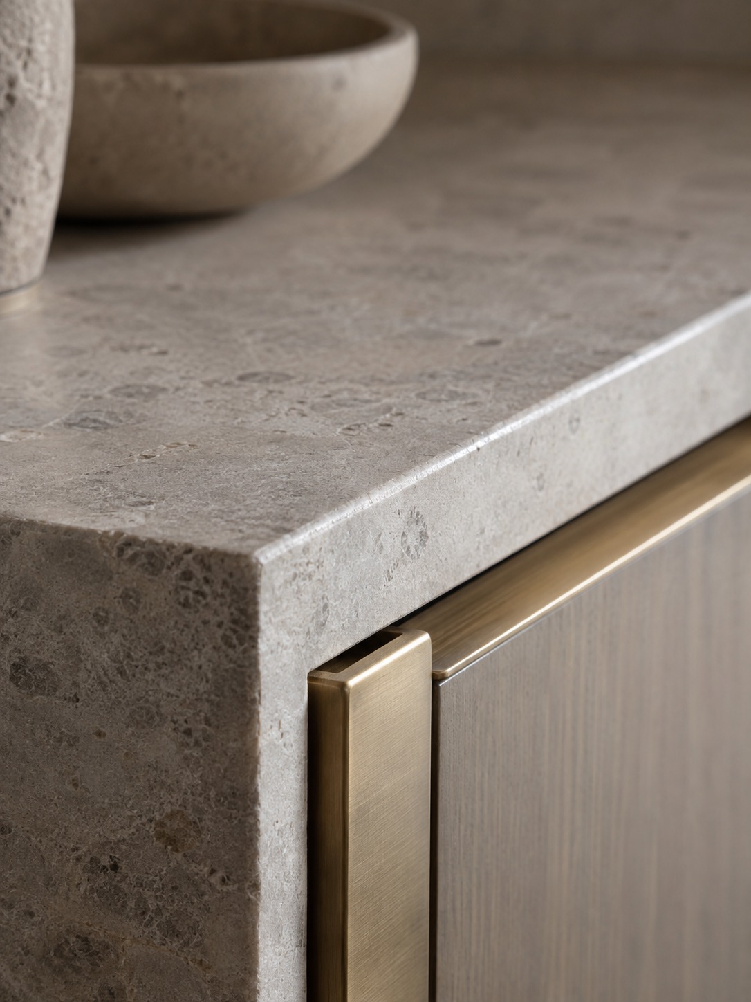 Close-up of a honed stone edge beside brushed brass hardware in soft daylight