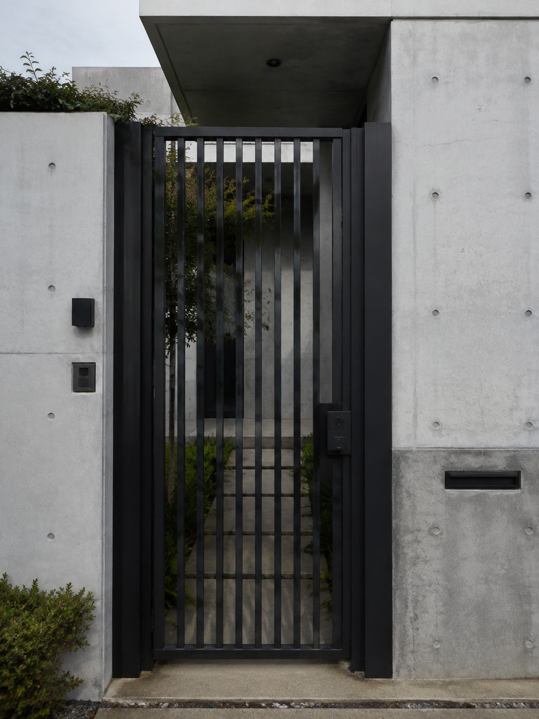 Integrated steel security gate A matte black steel security gate with vertical slats integrated into a clean concrete facade. | Sky Rye Design A matte black steel security gate with vertical slats integrated into a clean concrete facade.