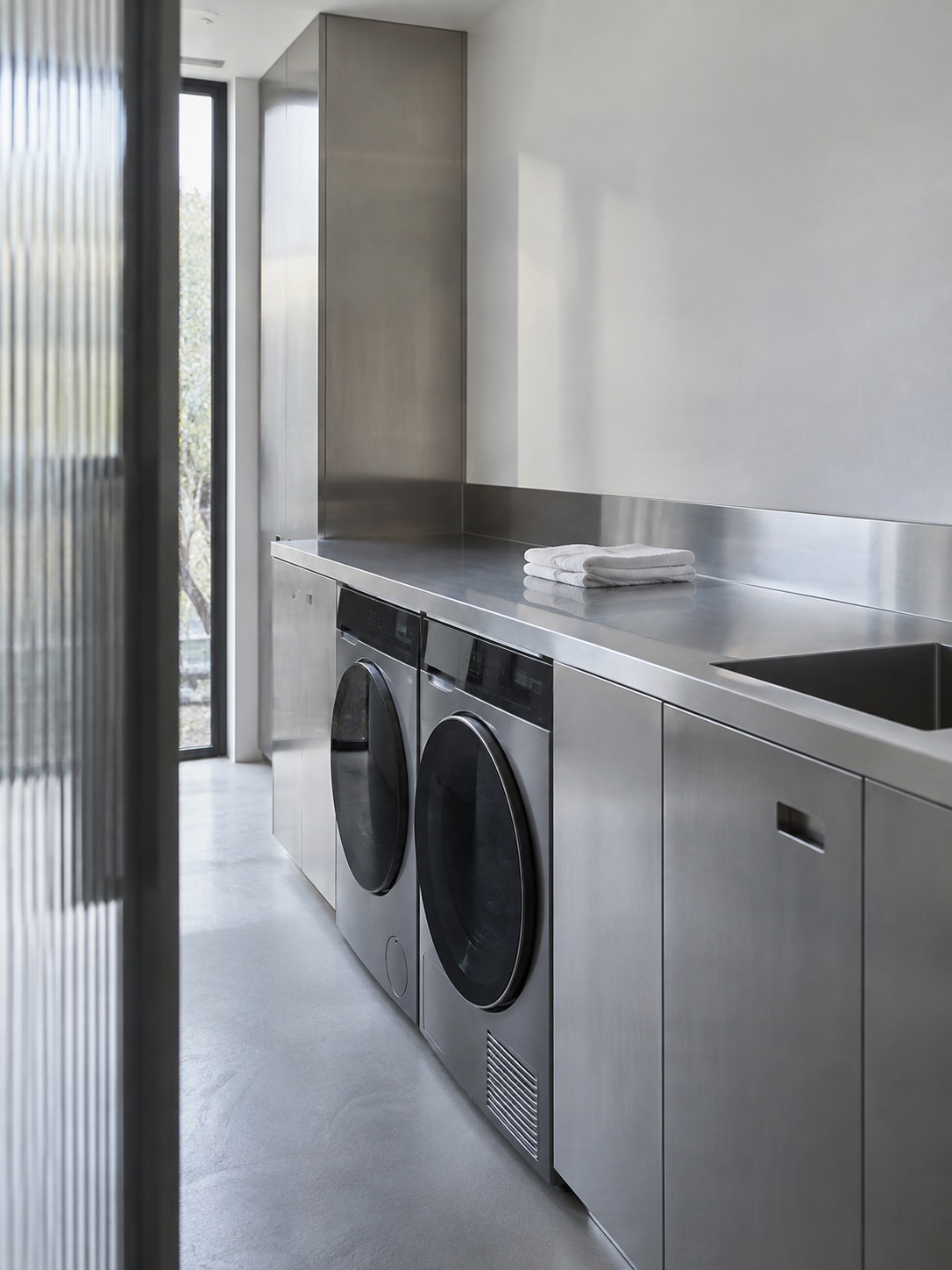 Stainless-steel laundry room Stainless-steel laundry cabinetry viewed through a ribbed-glass partition | Sky Rye Design Stainless-steel laundry cabinetry viewed through a ribbed-glass partition