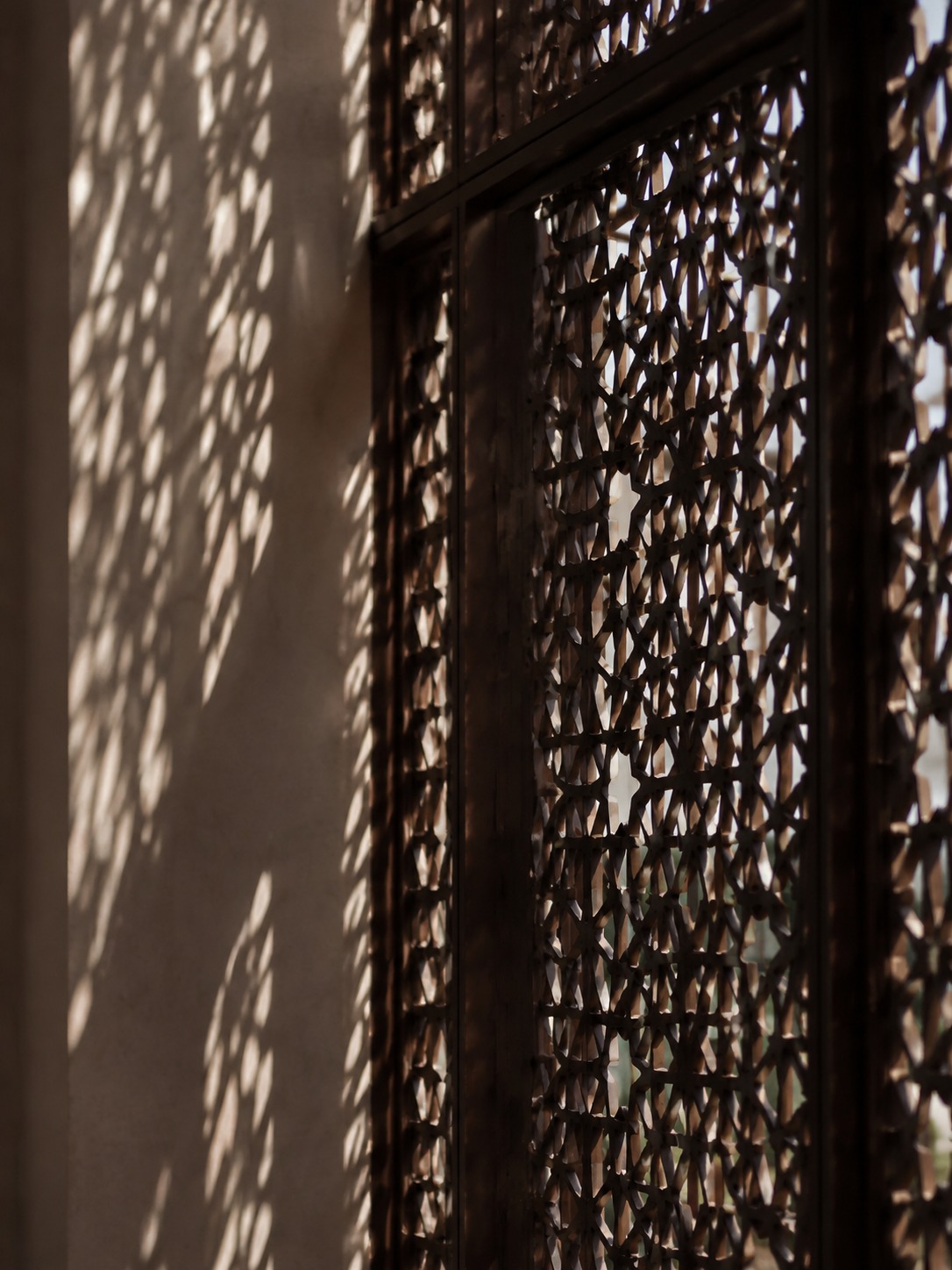 Modern Dubai facade with a mashrabiya-inspired perforated screen casting patterned light.