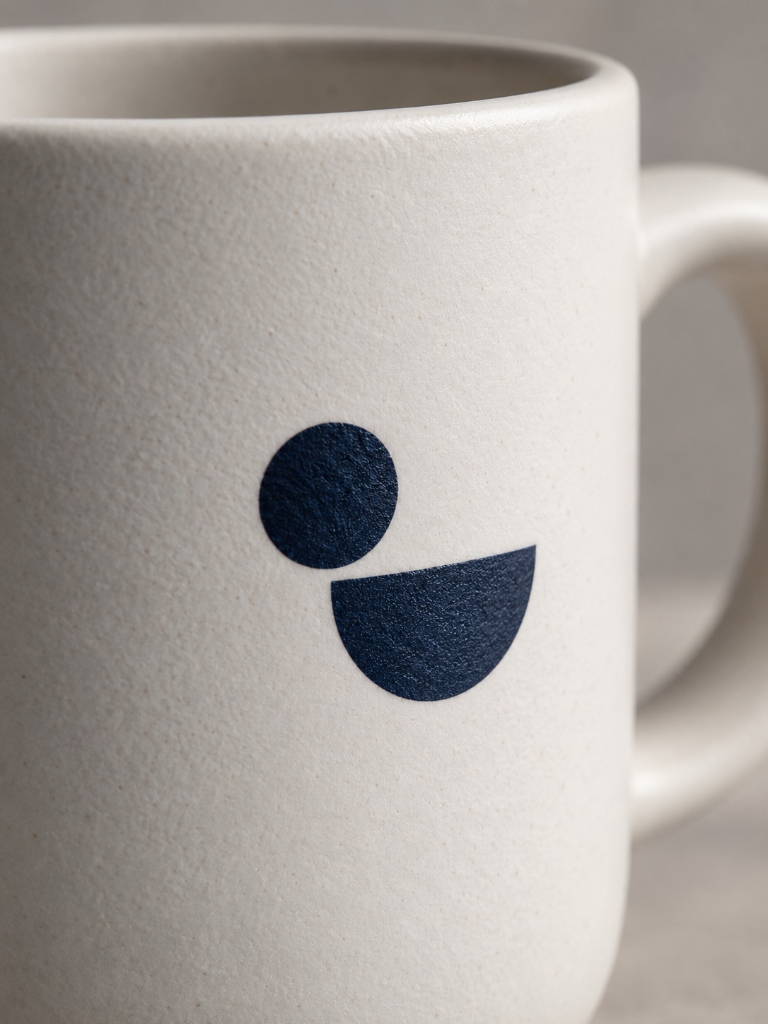Macro view of a simple abstract mark printed sharply on a matte white ceramic mug