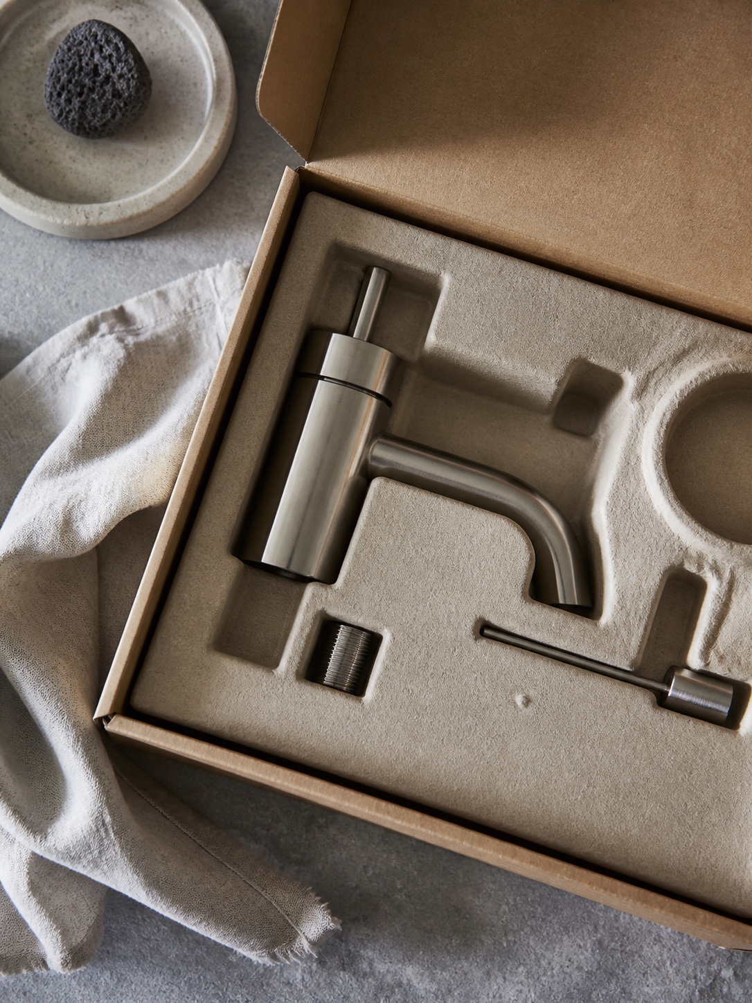 Minimal Recyclable Sustainable Fixture Packaging Minimal recyclable packaging for a sustainable bathroom fixture laid out in soft studio light. | Sky Rye Design Minimal recyclable packaging for a sustainable bathroom fixture laid out in soft studio light.
