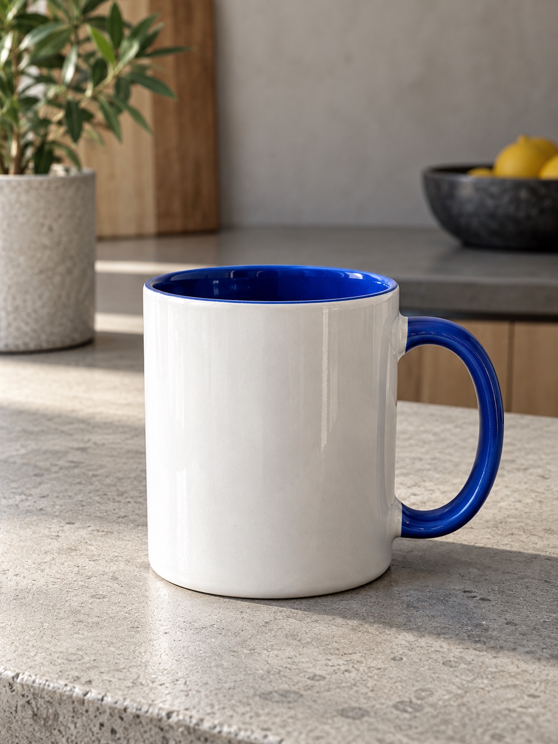 White ceramic mug with a cobalt blue interior and handle on a concrete kitchen counter