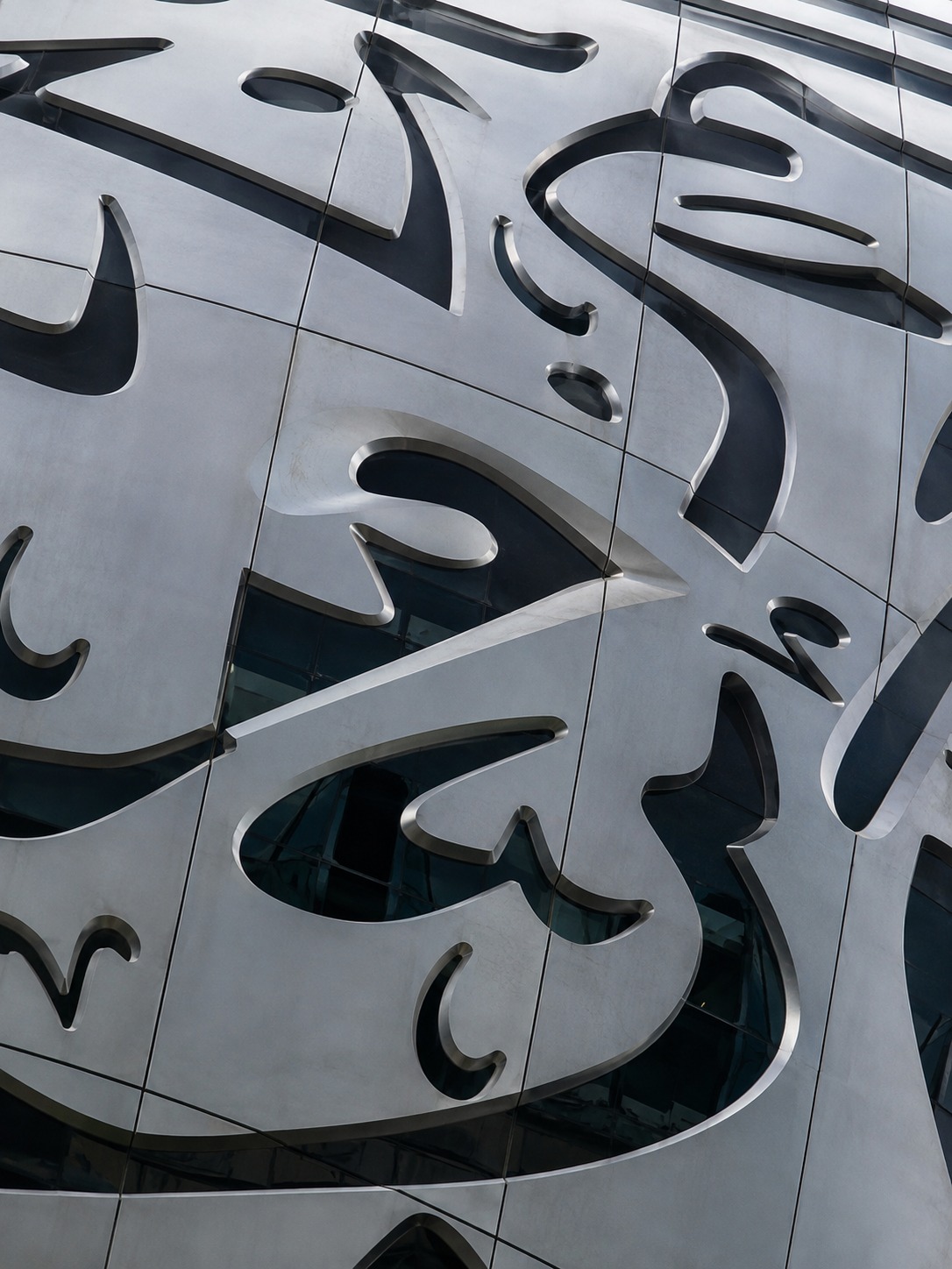 Close detail of Museum of the Future steel facade panels with calligraphy-shaped openings.